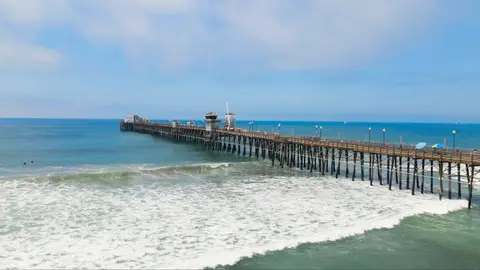 Oceanside Pier from the air, with waves breaking along the beach