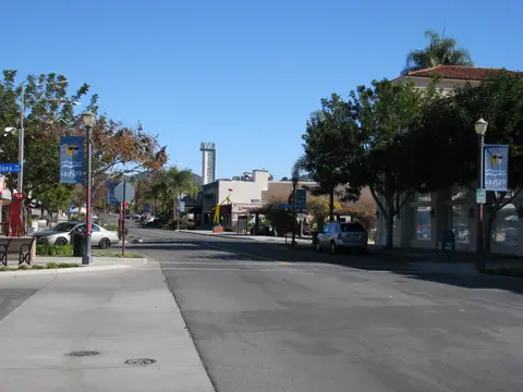 Main Street in downtown Vista, California, with palm trees and a sloping road